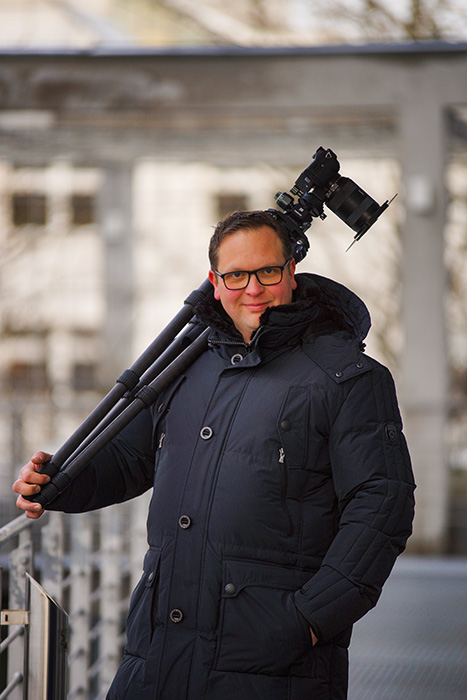Portrait Robert Eger mit Kamera über der Schulter